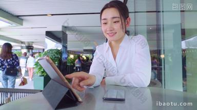 年轻女人坐在咖啡馆里使用平板电脑